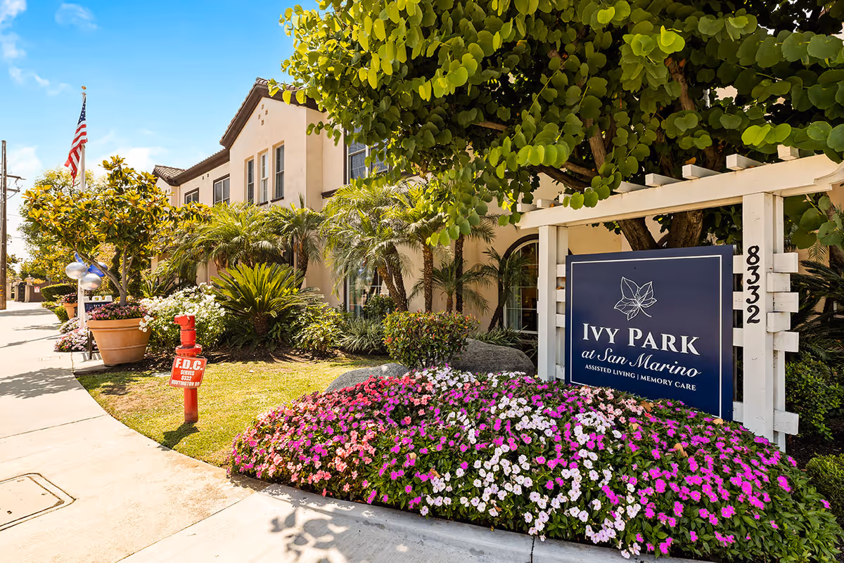 Exterior view of the Ivy Park at San Marino building with its entrance sign, manicured flowerbeds, and trees.