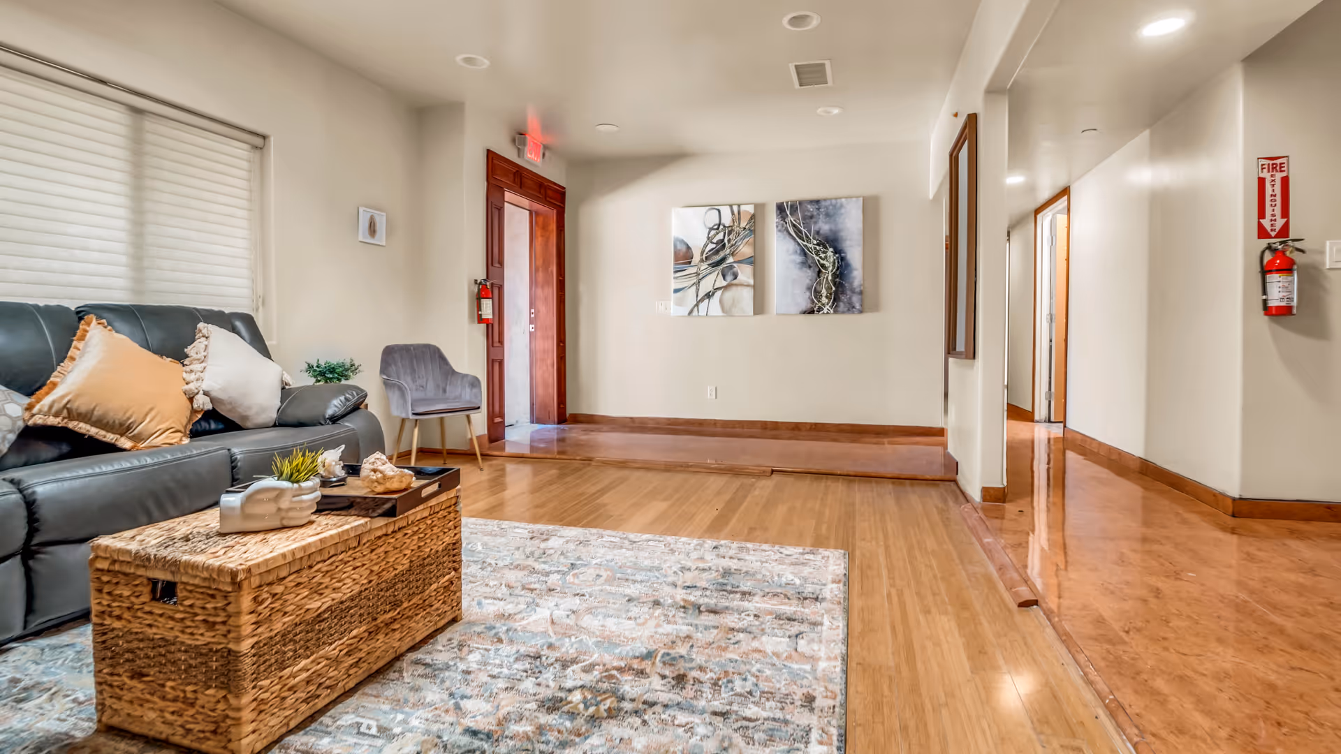 Cozy lobby with leather sofa, coffee table, rug, artwork, and hallway to rooms.
