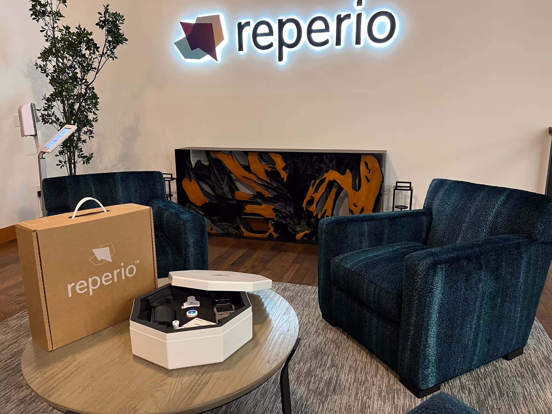 Lobby reception area featuring Reperio Health sign, teal armchairs, and a round coffee table.