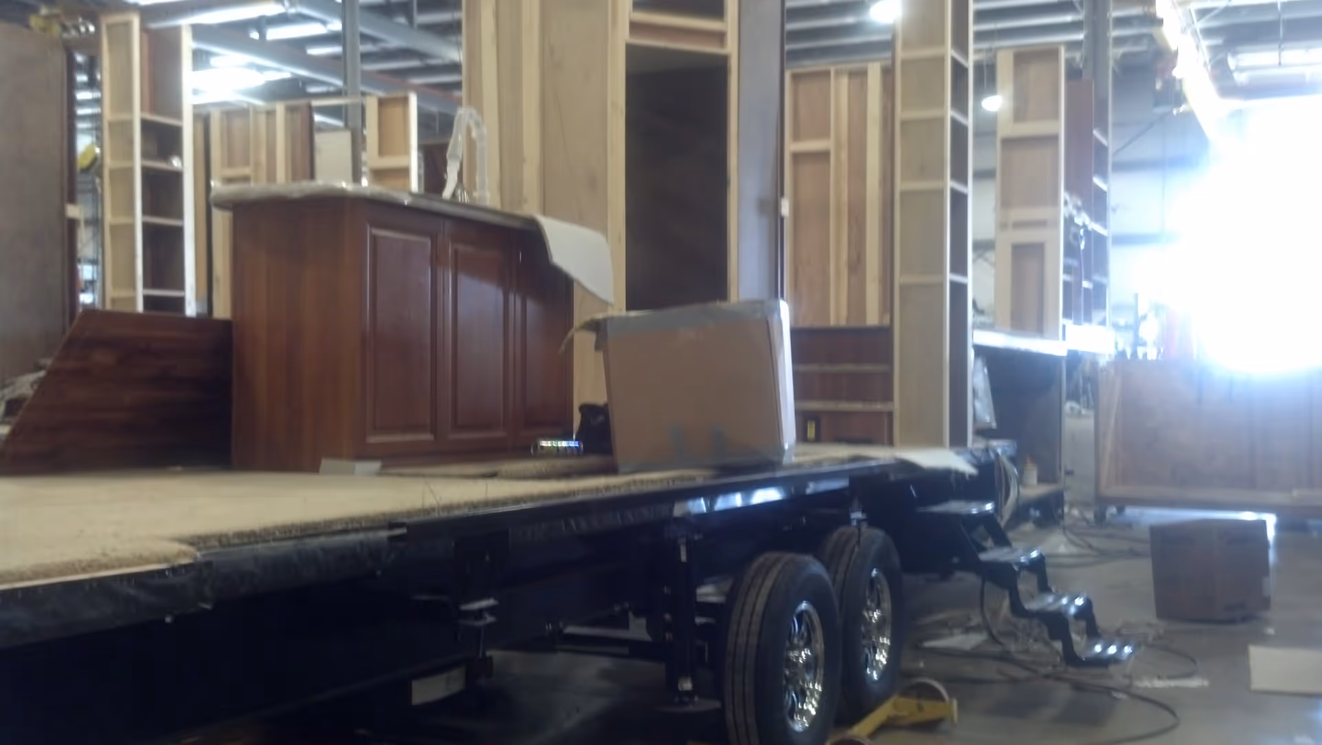 Interior under construction shows wooden cabinets, scaffolding, and a mobile stage trailer with boxes.