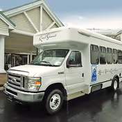 White shuttle bus parked in front of Quail Summit senior living facility exterior.