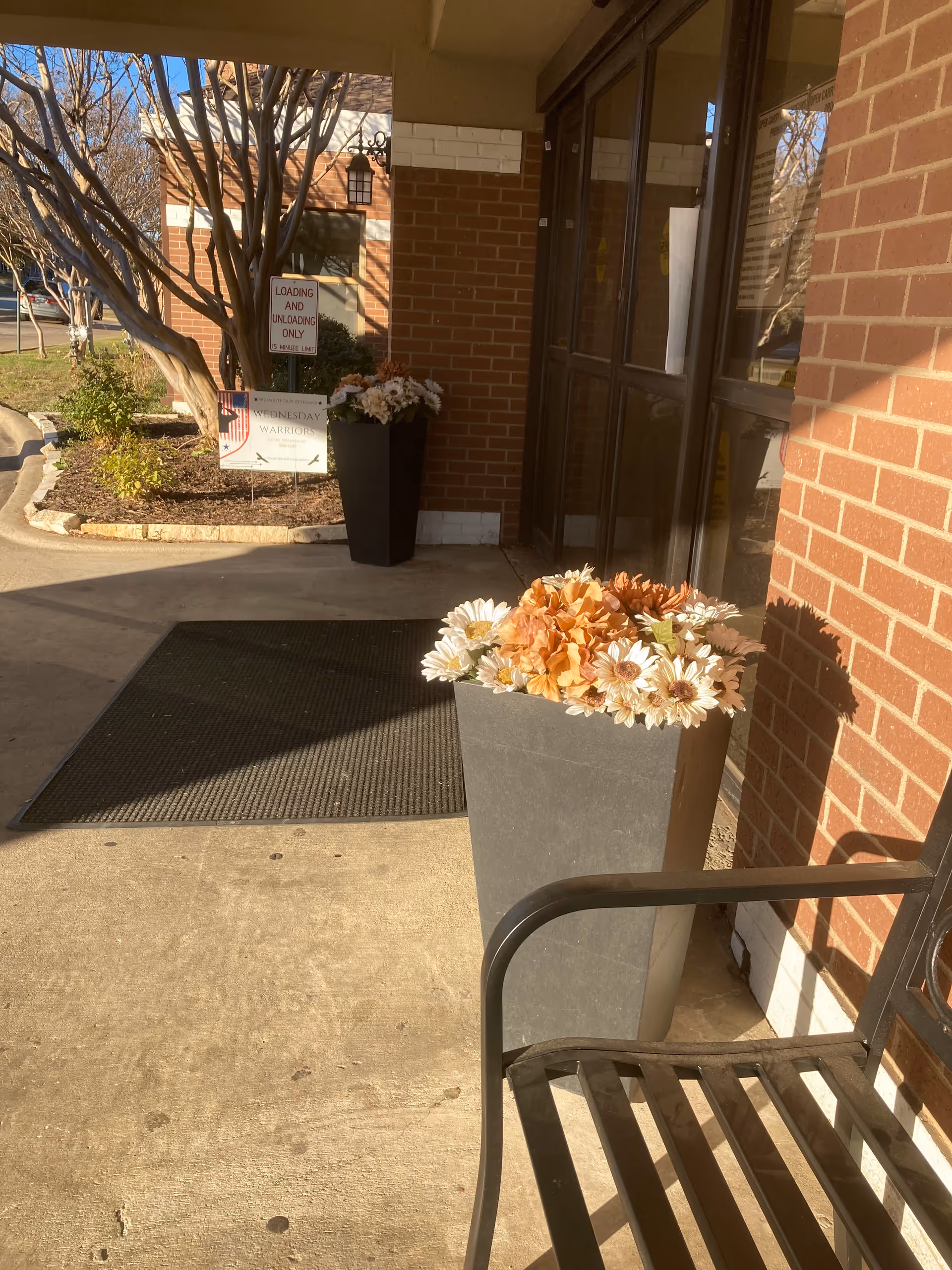 Entrance of Oakmont Guest Care Center with brick exterior, glass doors, and potted flowers.