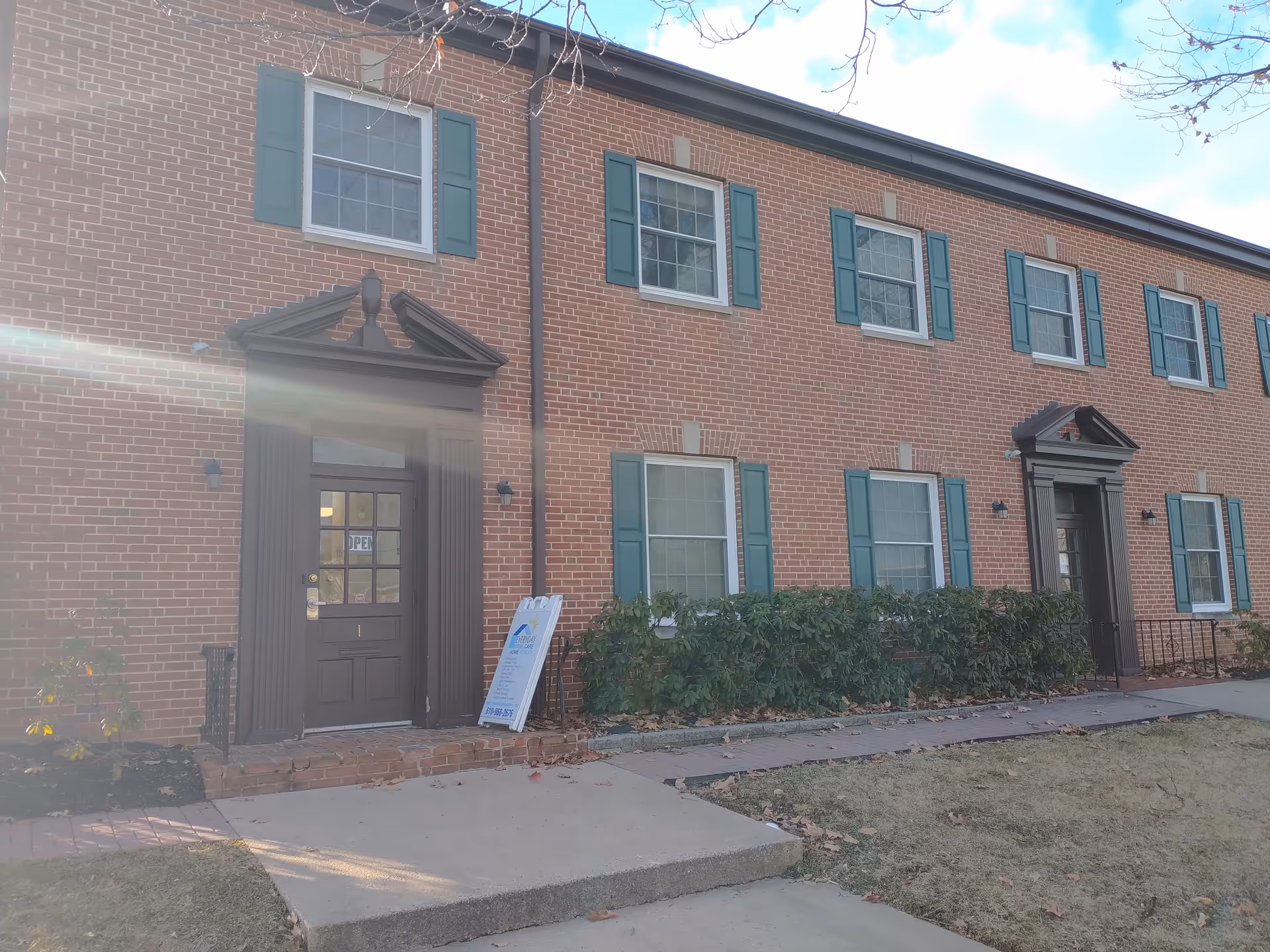 Brick senior living building with green shutters and two front entrances.
