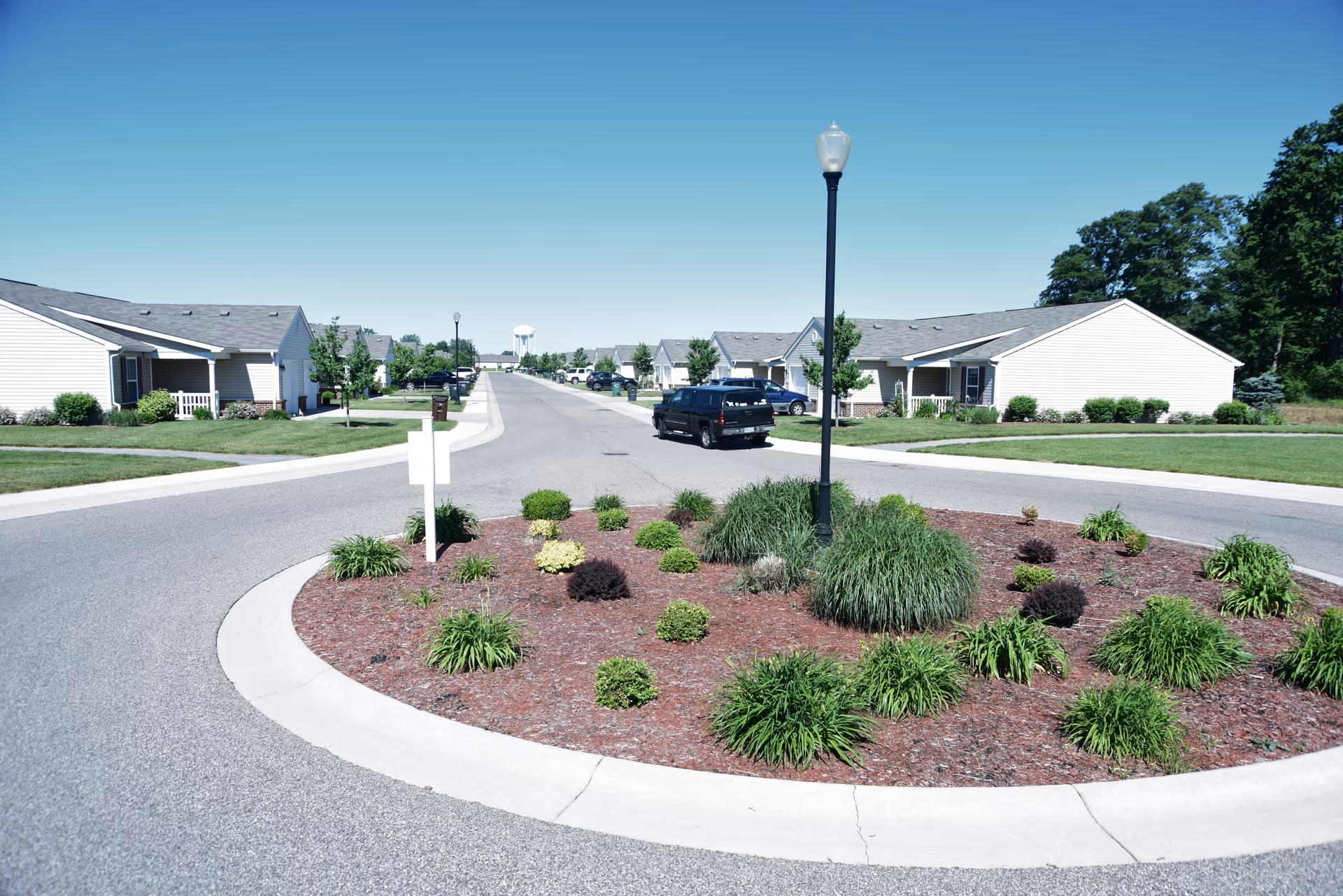 Wide view of a senior living campus with circular island, street, and single-story buildings.