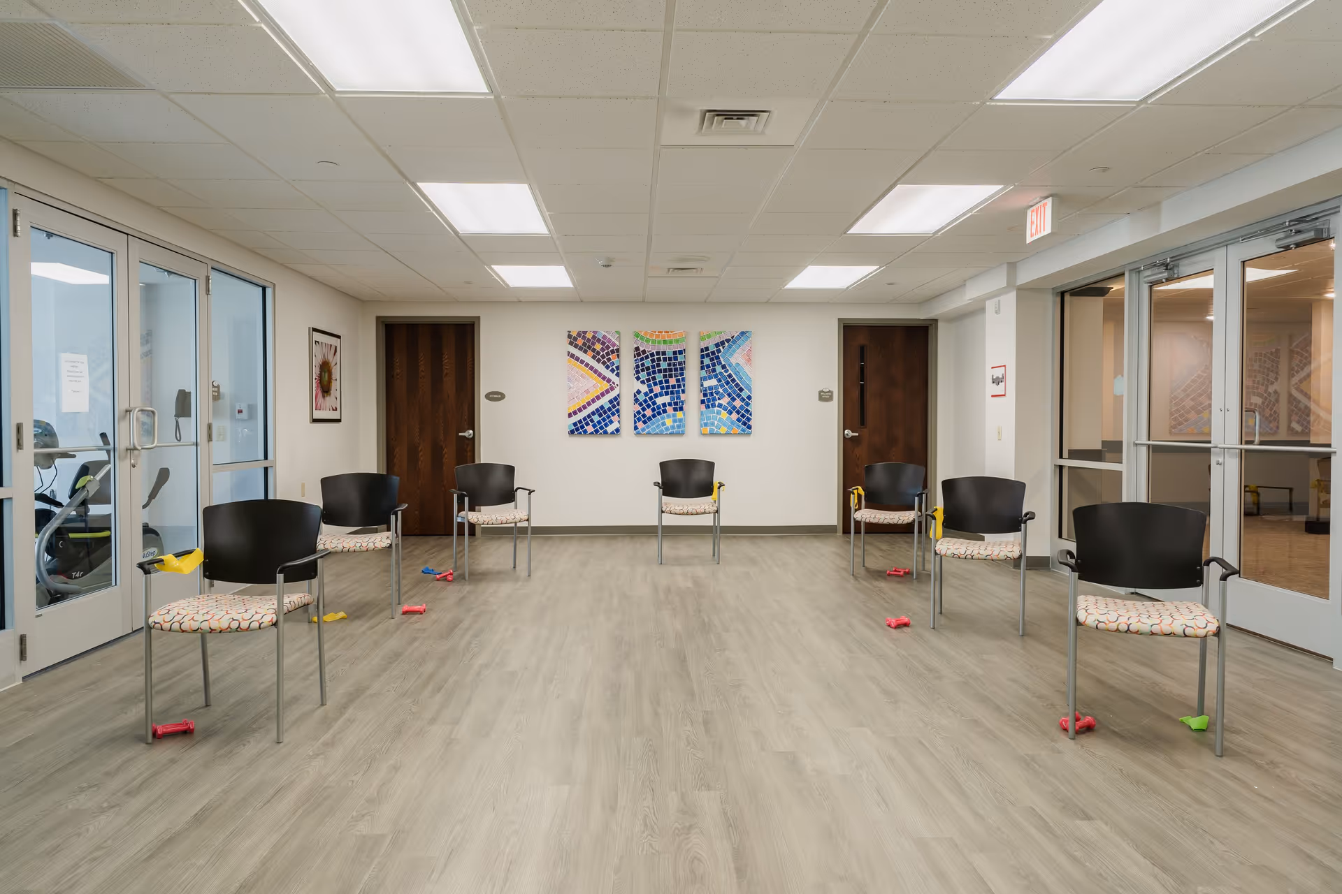 Bright, empty senior living common area with multiple chairs arranged around the room.