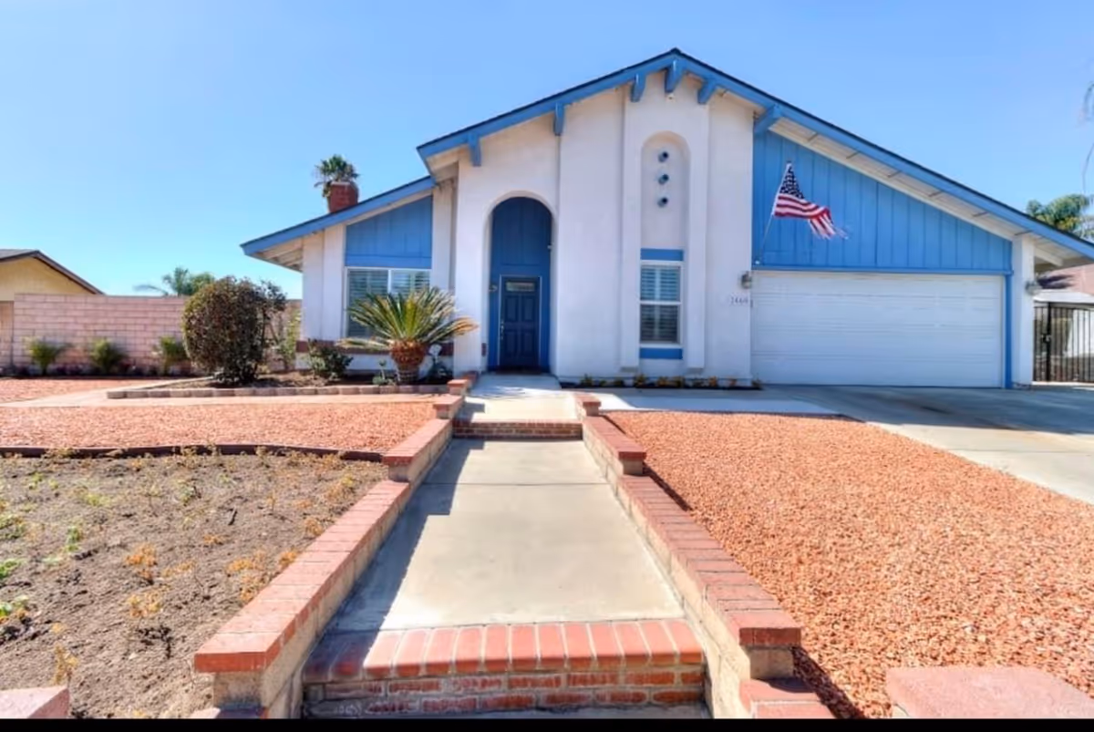 Front view of Bella Maison Assisted Living facility with blue trim and flag.