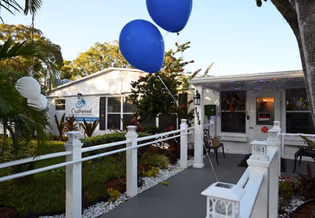 Exterior view of a senior living center entrance with white railings and balloons.