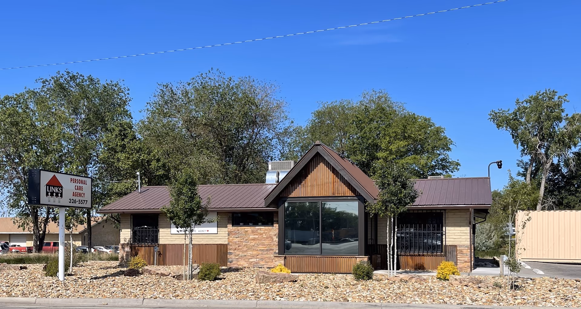 Front view of a single-story building with stone and wood accents, sign reading Links II