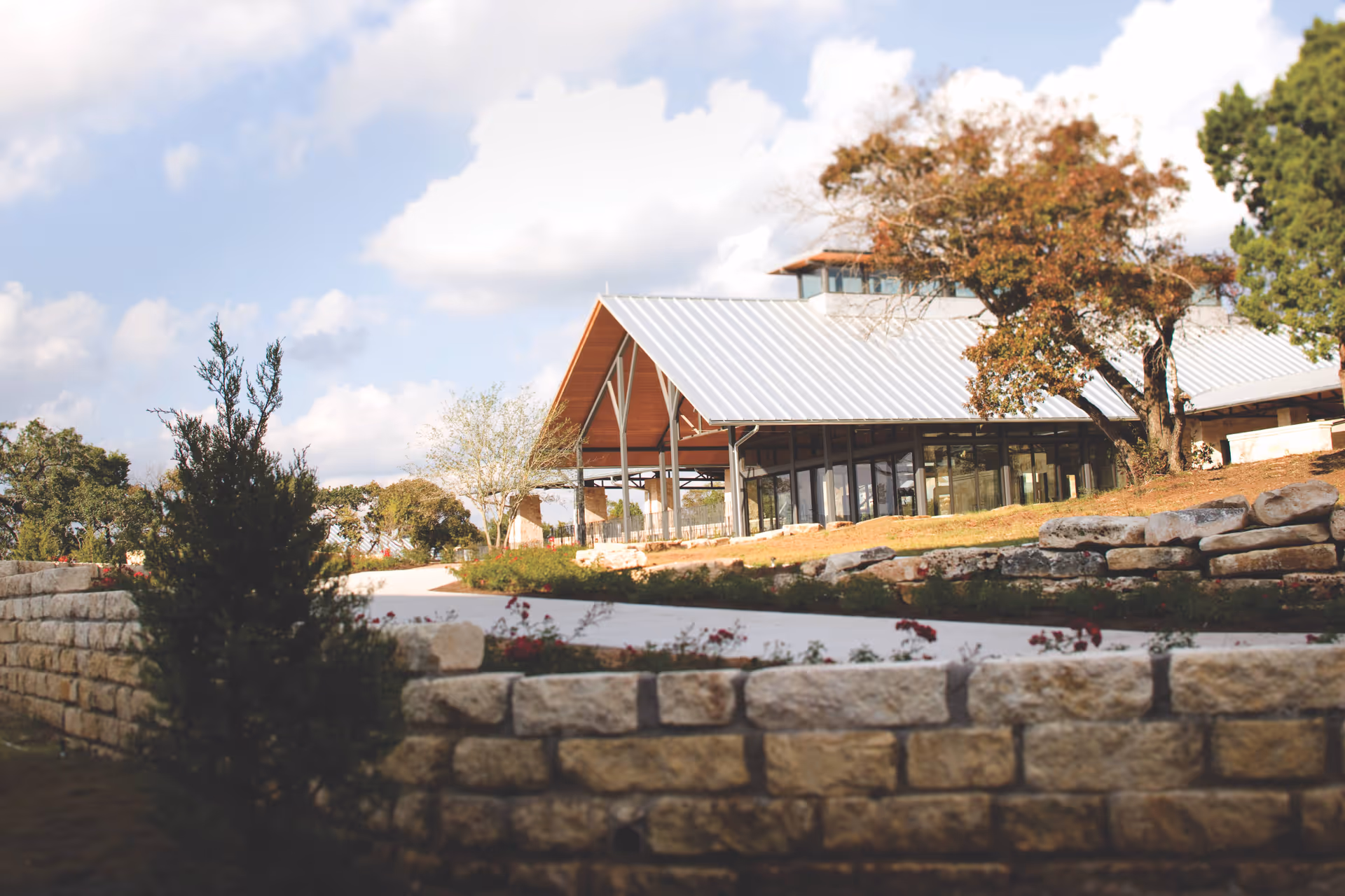 Exterior view of Querencia at Barton Creek with stone wall and glass entrance.