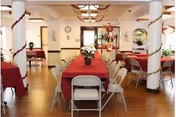 A dining hall with red tablecloths, chairs, and striped columns inside a senior facility.