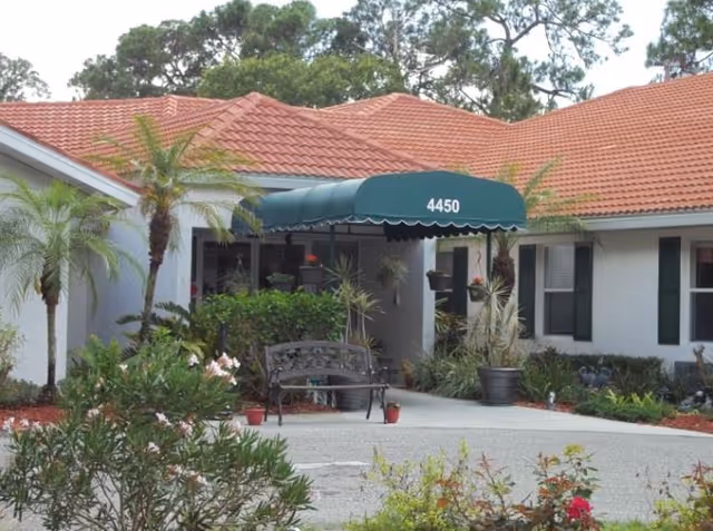 Senior living facility entrance with a green awning and landscaped front yard.