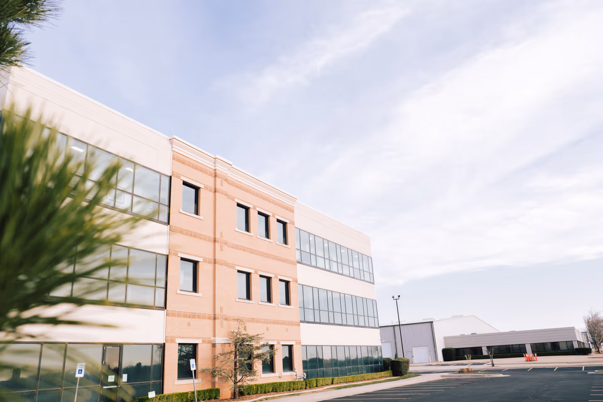 Exterior view of a brick and glass senior care facility with a parking lot.