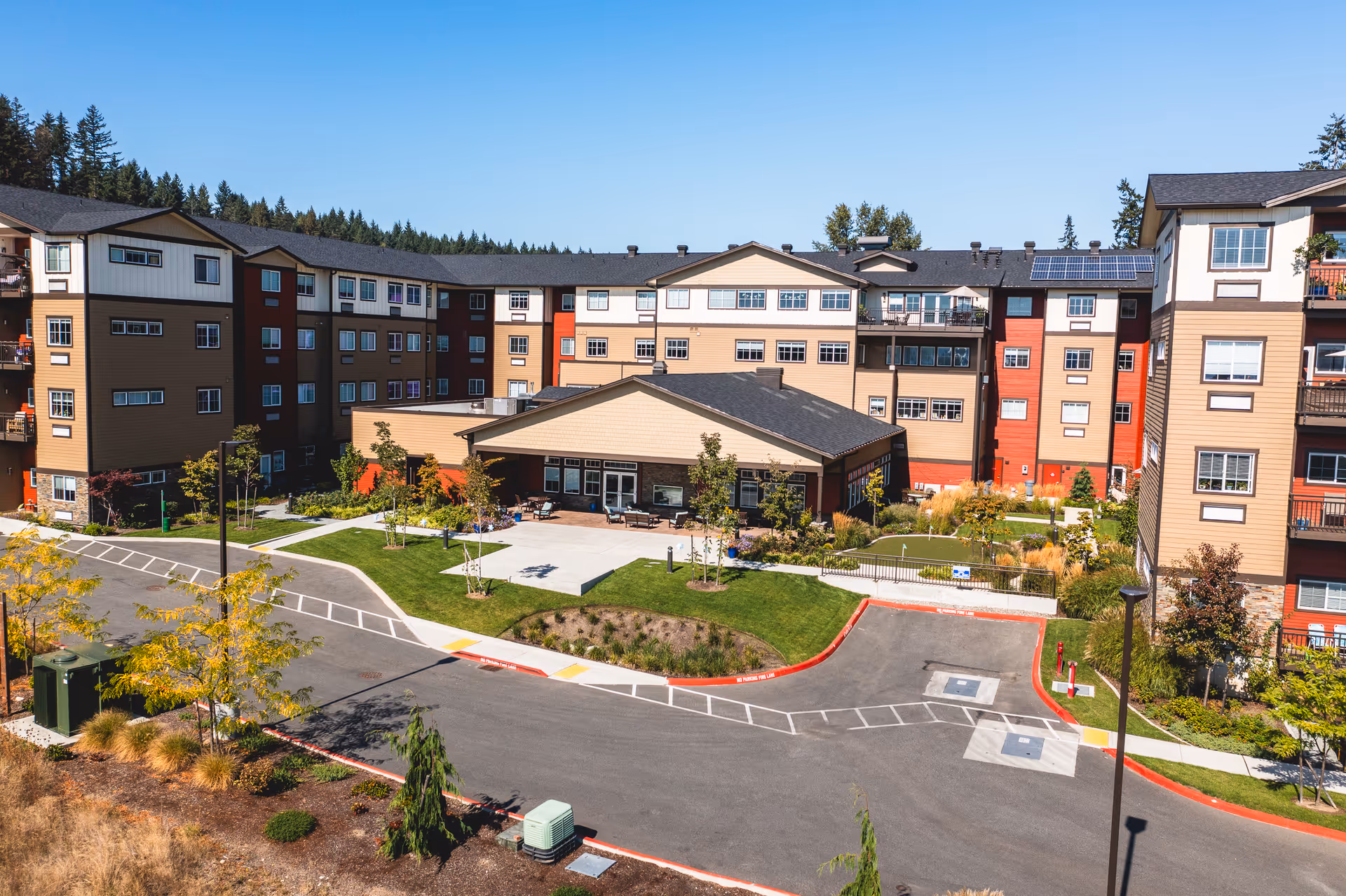Exterior view of a multi-story senior living building surrounding a landscaped courtyard and parking area.