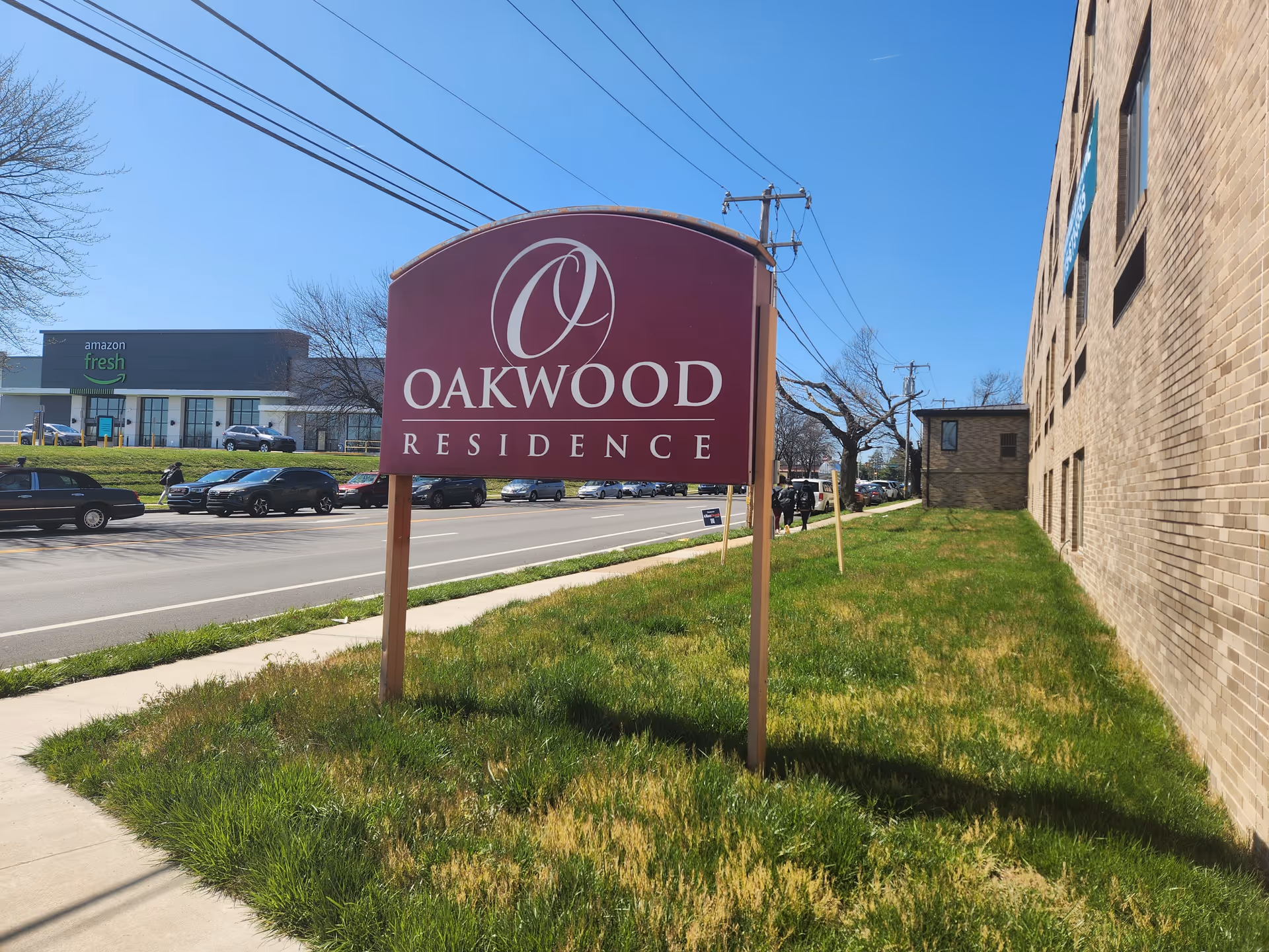 Oakwood Residence sign on a grassy lawn beside a brick building.