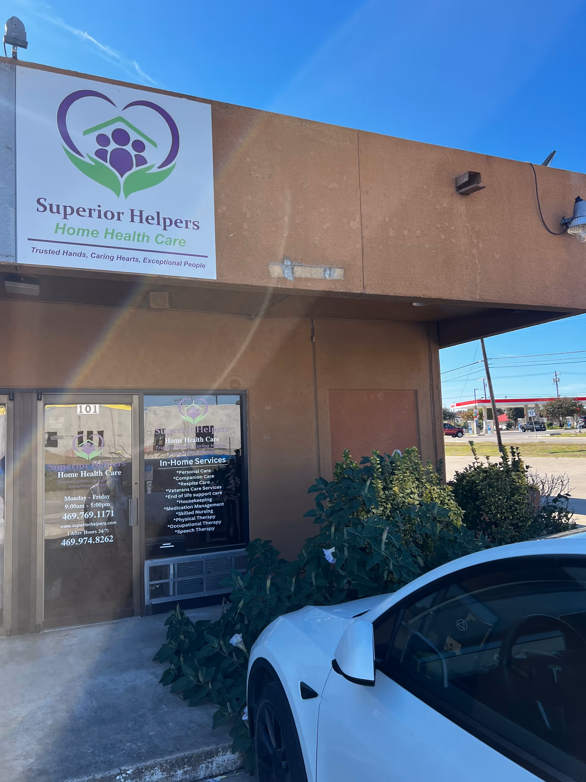 Exterior of Superior Helpers building with sign, bushes, and a parked white car
