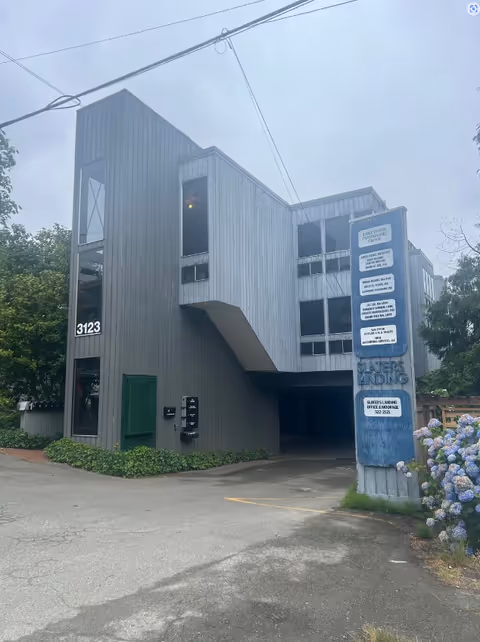 Exterior view of a gray angular building with a parking entrance and blue signage.