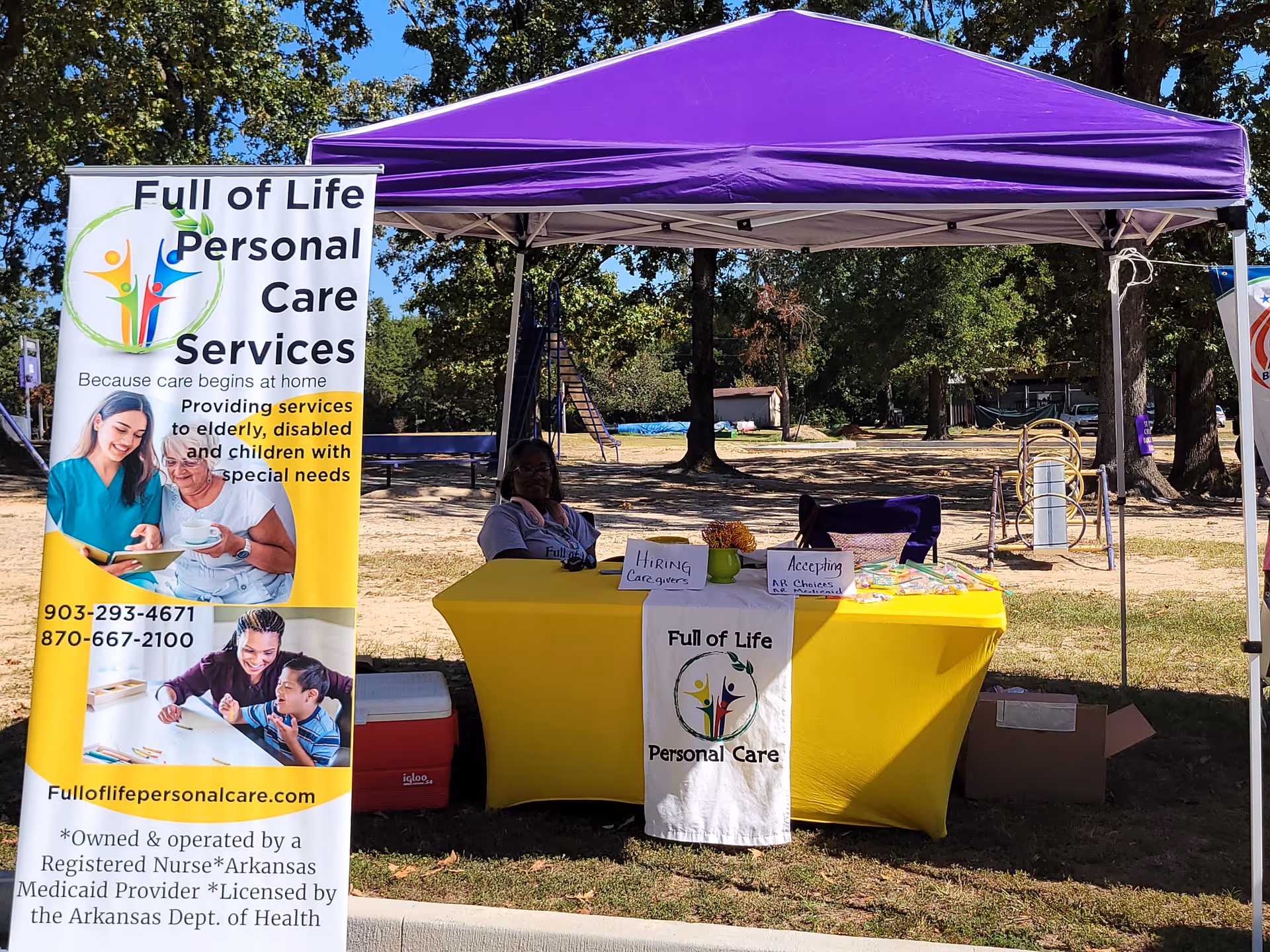 Outdoor booth with a purple canopy and Full of Life Personal Care Services banner