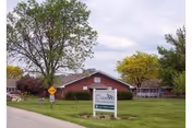 Exterior view of Oakwood Specialty Care facility with a green lawn and trees.