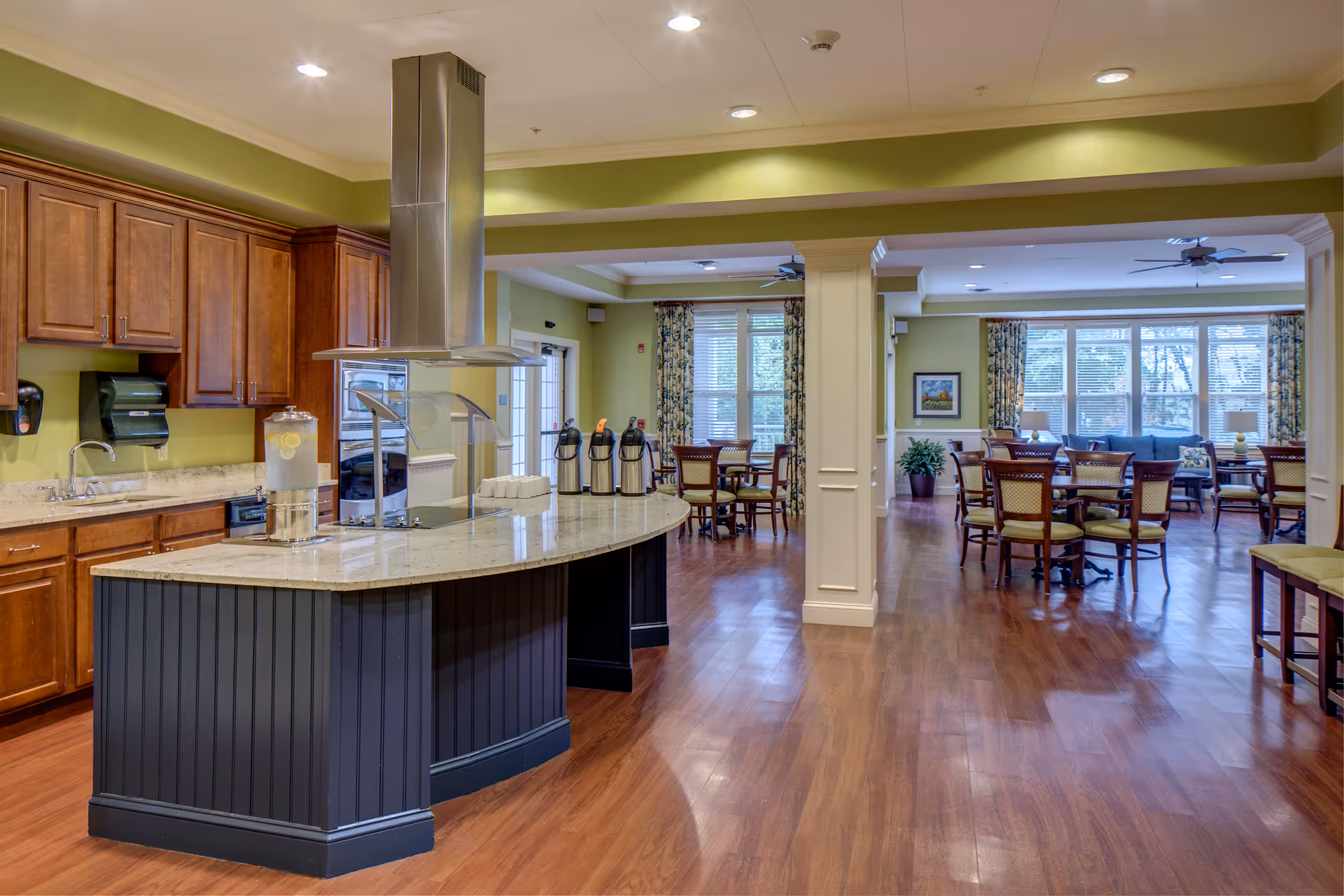 Bright open dining area with tables, chairs, and a curved kitchen island.