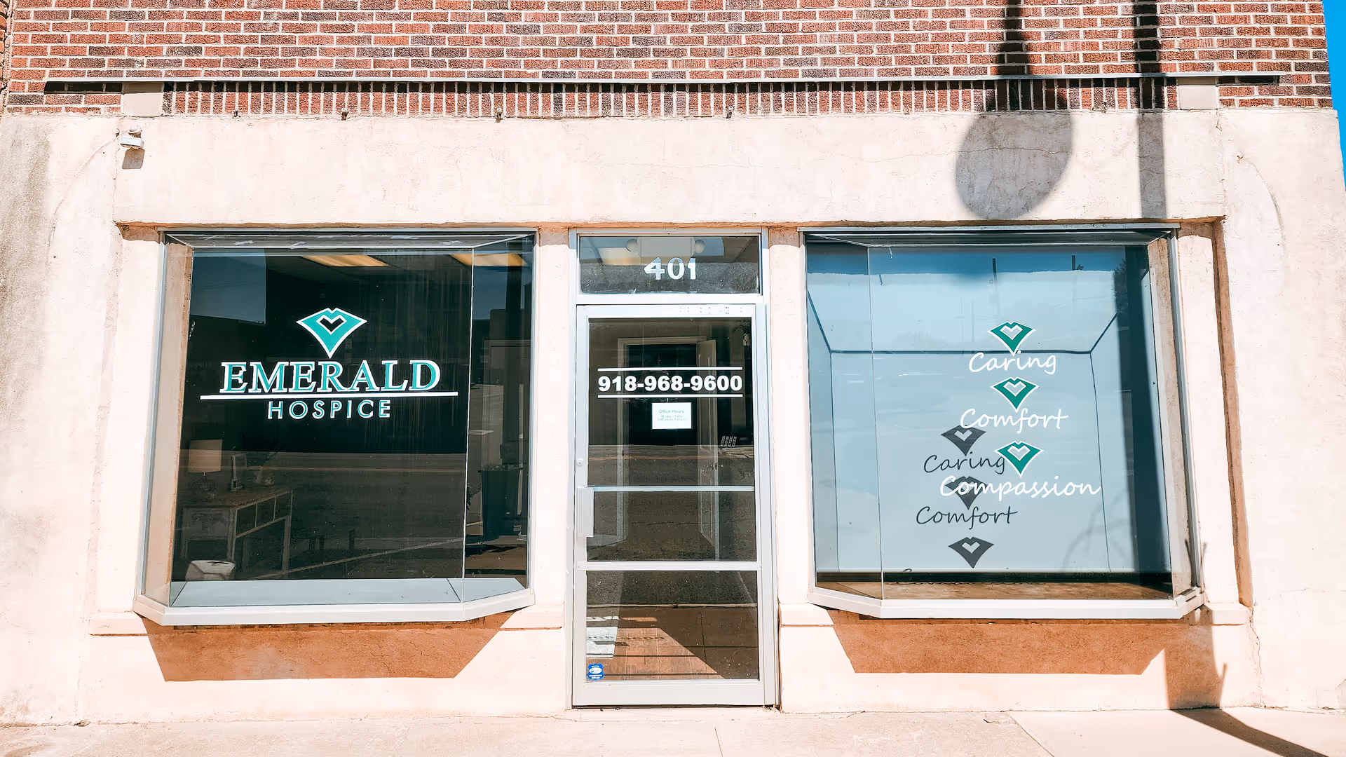 Exterior storefront for Emerald Hospice with glass doors and care-themed window decals