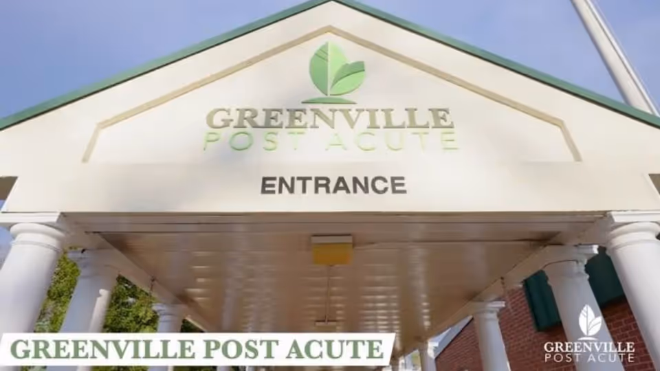 Entrance to Greenville Post Acute with white columns and a green logo