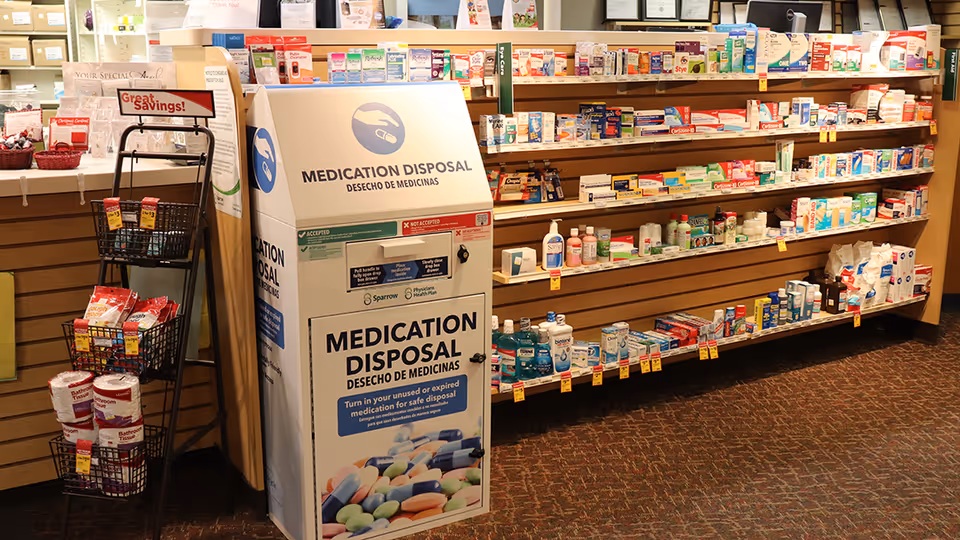 Medication disposal kiosk beside medicine shelves inside an indoor facility.