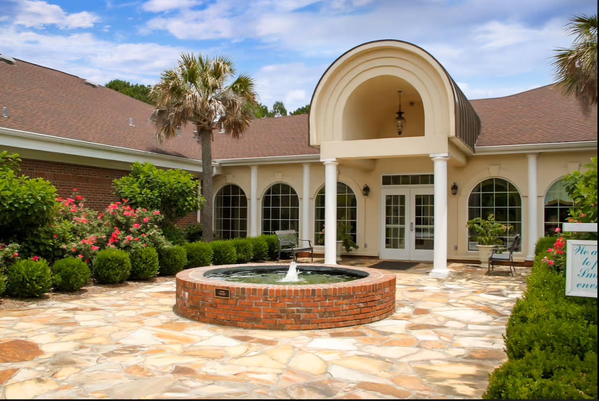 Exterior courtyard of VIA Health Partners Laurens County with a brick fountain and arched entrance.