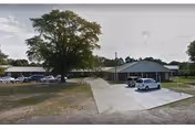 Exterior view of Palmetto Ridge Assisted Living & Memory Care facility with driveway and parked cars.