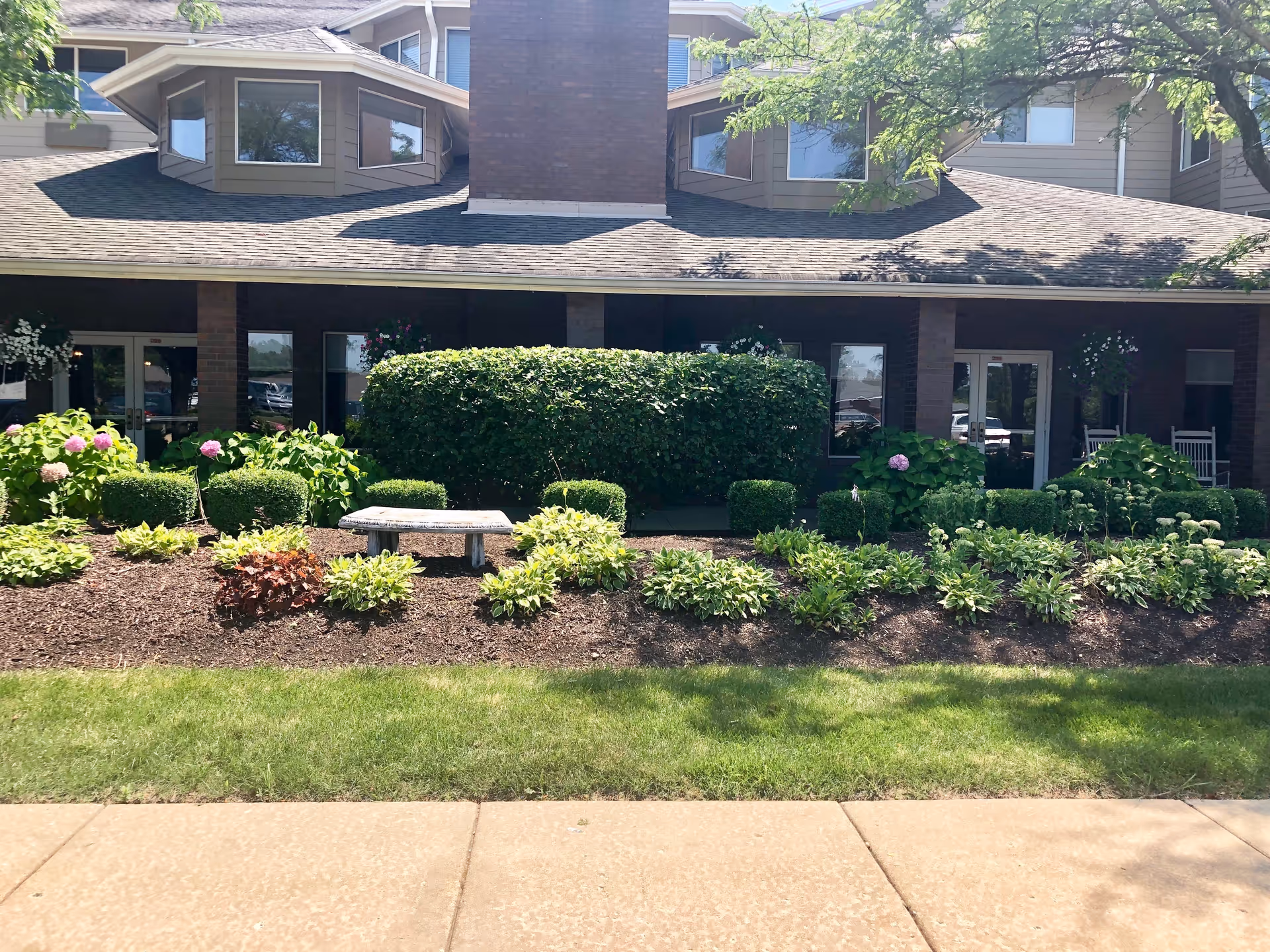 Exterior view of Solstice Senior Living at Joliet with landscaped shrubs and a bench.