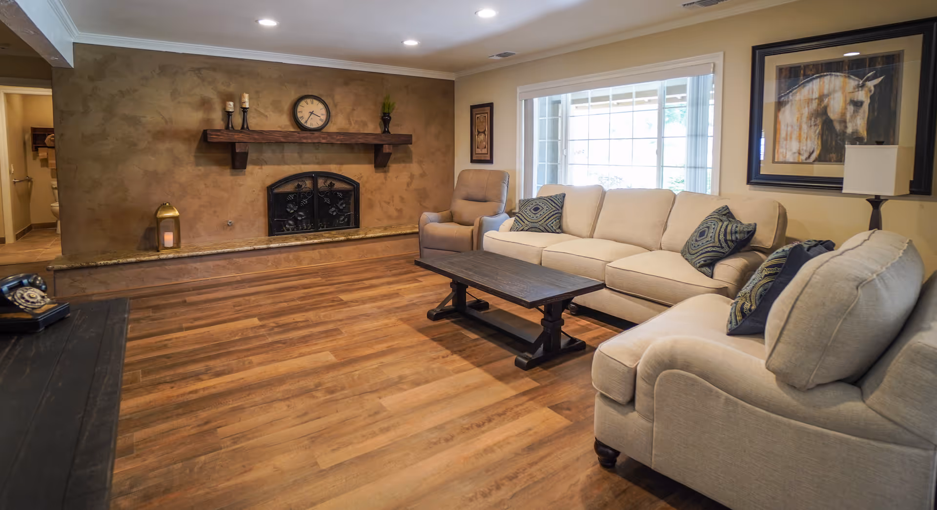 Spacious living room with beige sofa, wood floor, fireplace, and large window.
