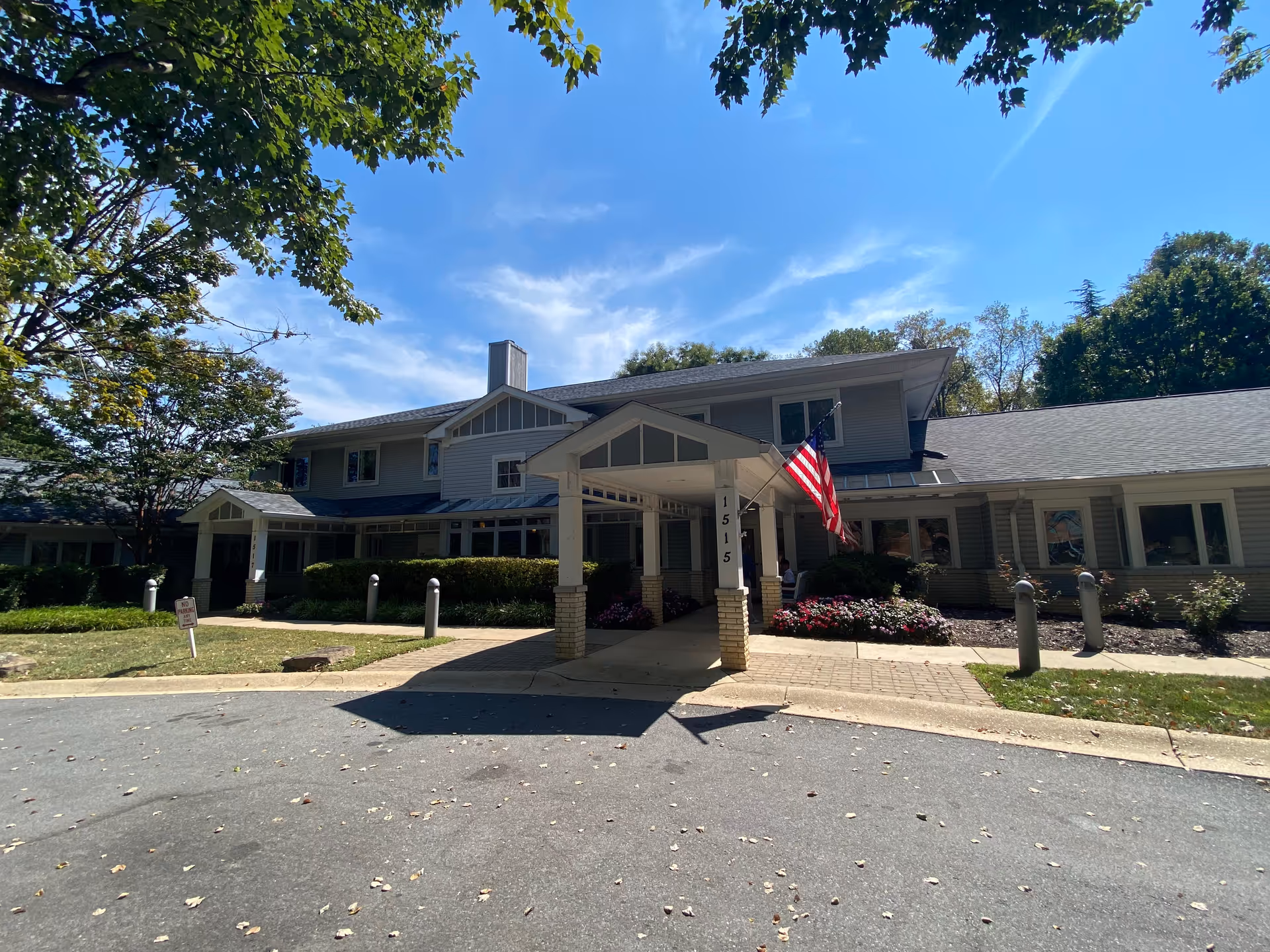 Exterior view of Raphael House senior living facility front entrance with flag and landscaping.