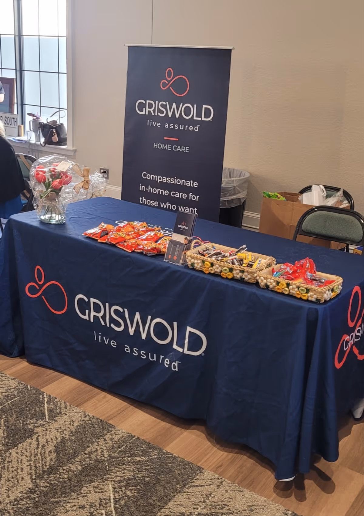 Promotional table with Griswold Home Care banner and assorted snacks in an interior display.