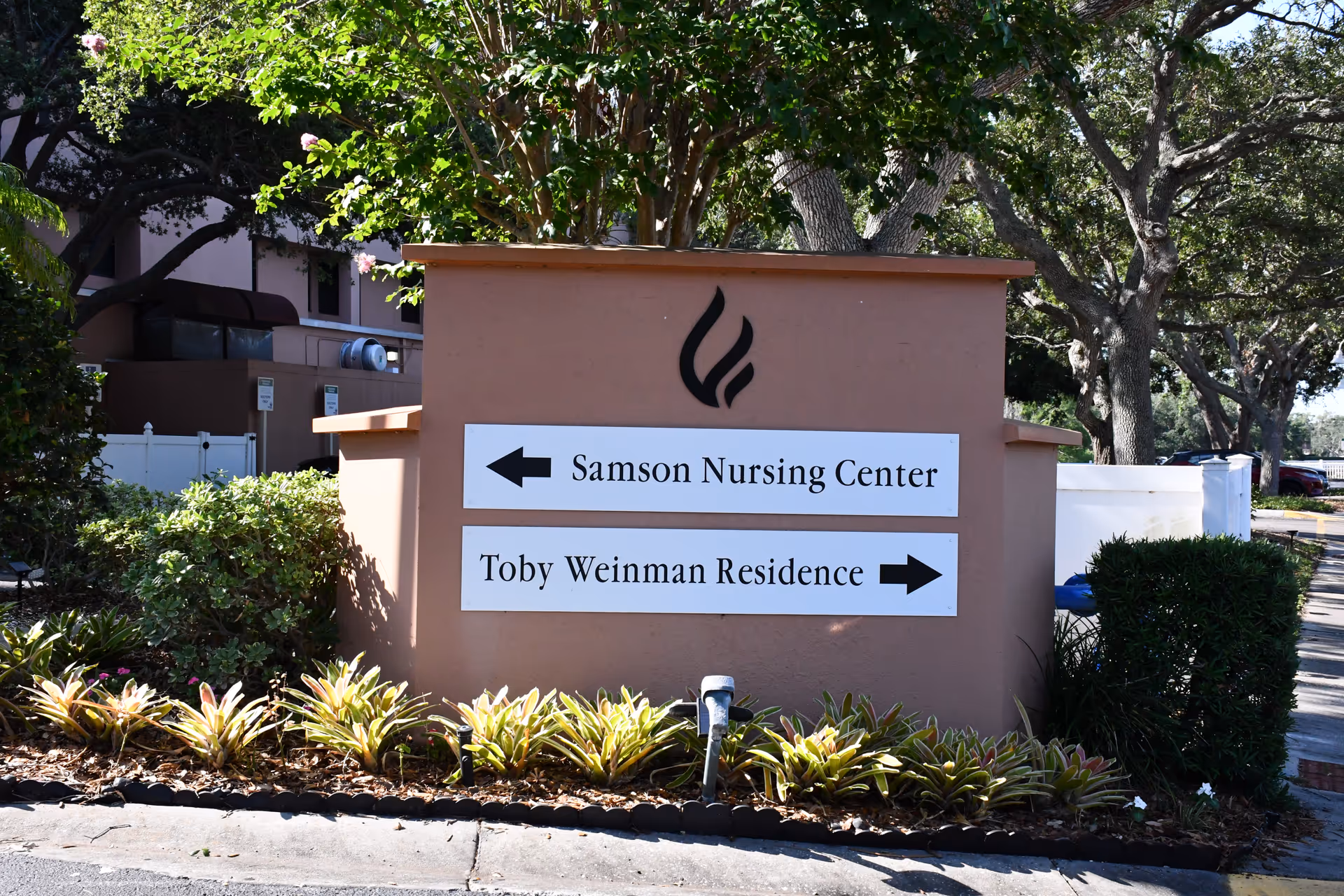Outdoor sign on building front shows directions to Samson Nursing Center and Toby Weinman Residence.