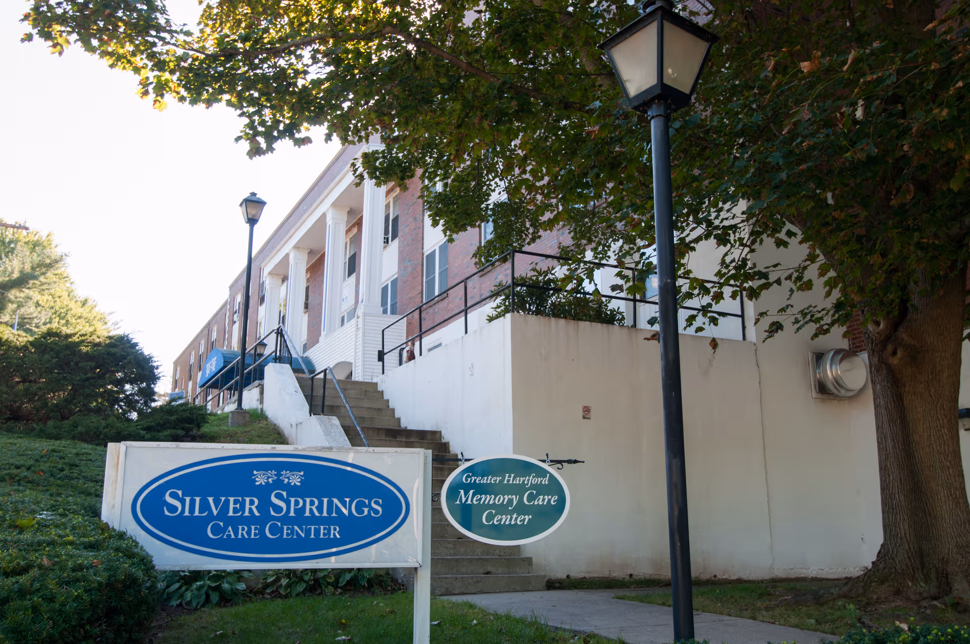 Exterior view of Silver Springs Care Center with signs, stairs, and surrounding trees.