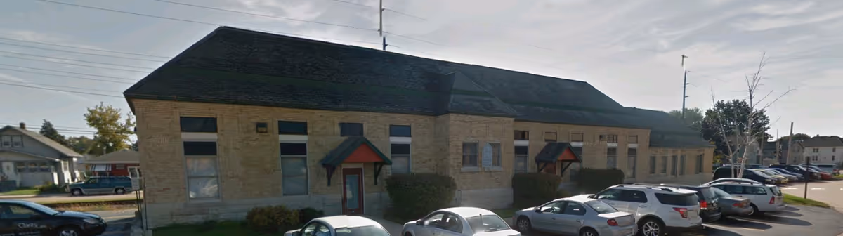 Exterior view of a Clarity Care senior living facility with parked cars along the side.