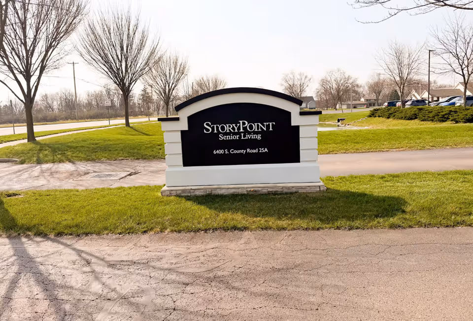 StoryPoint Senior Living sign on a grassy roadside median by a road.