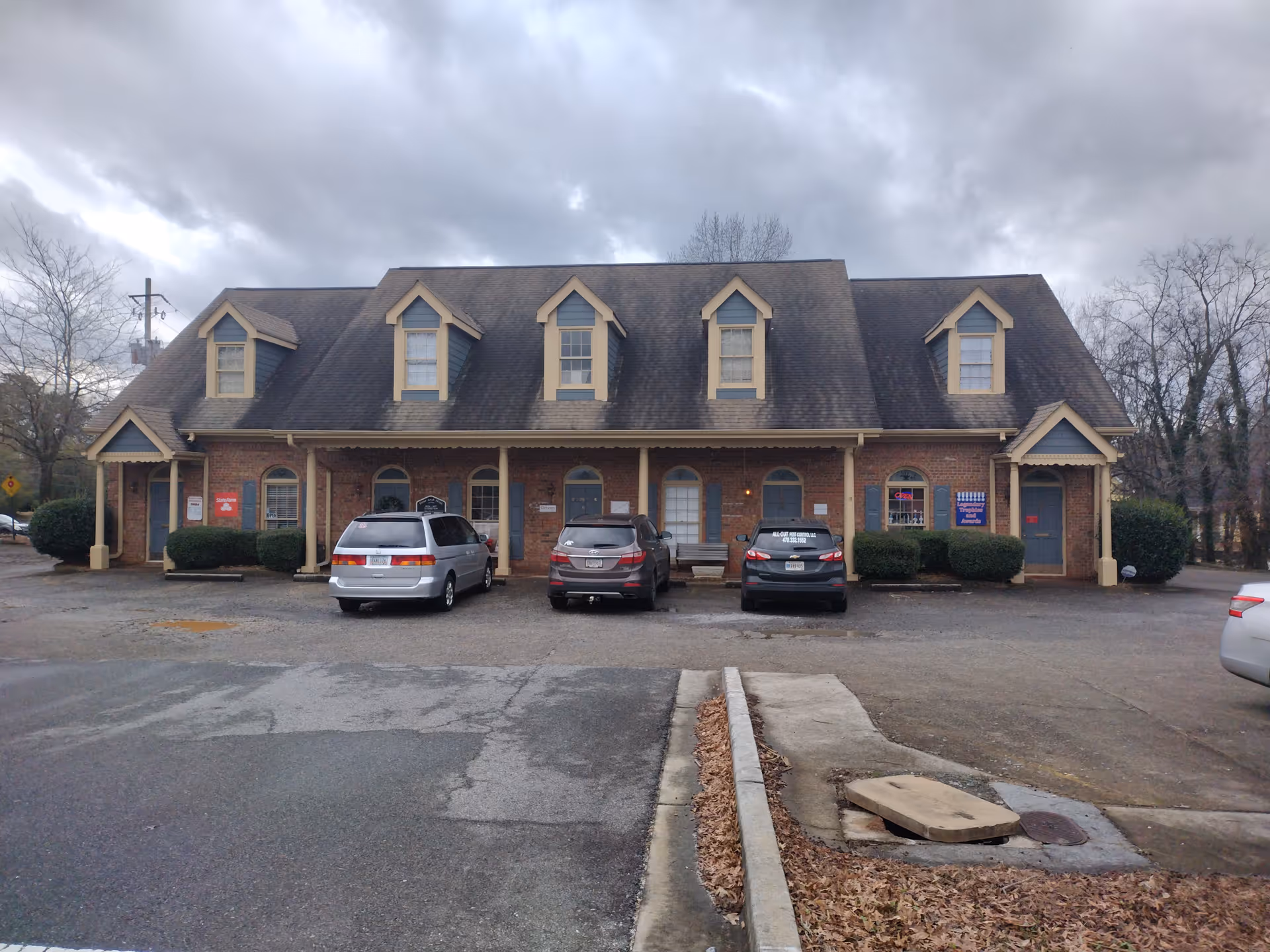 Brick front-facing senior living facility with dormer windows and parked cars.