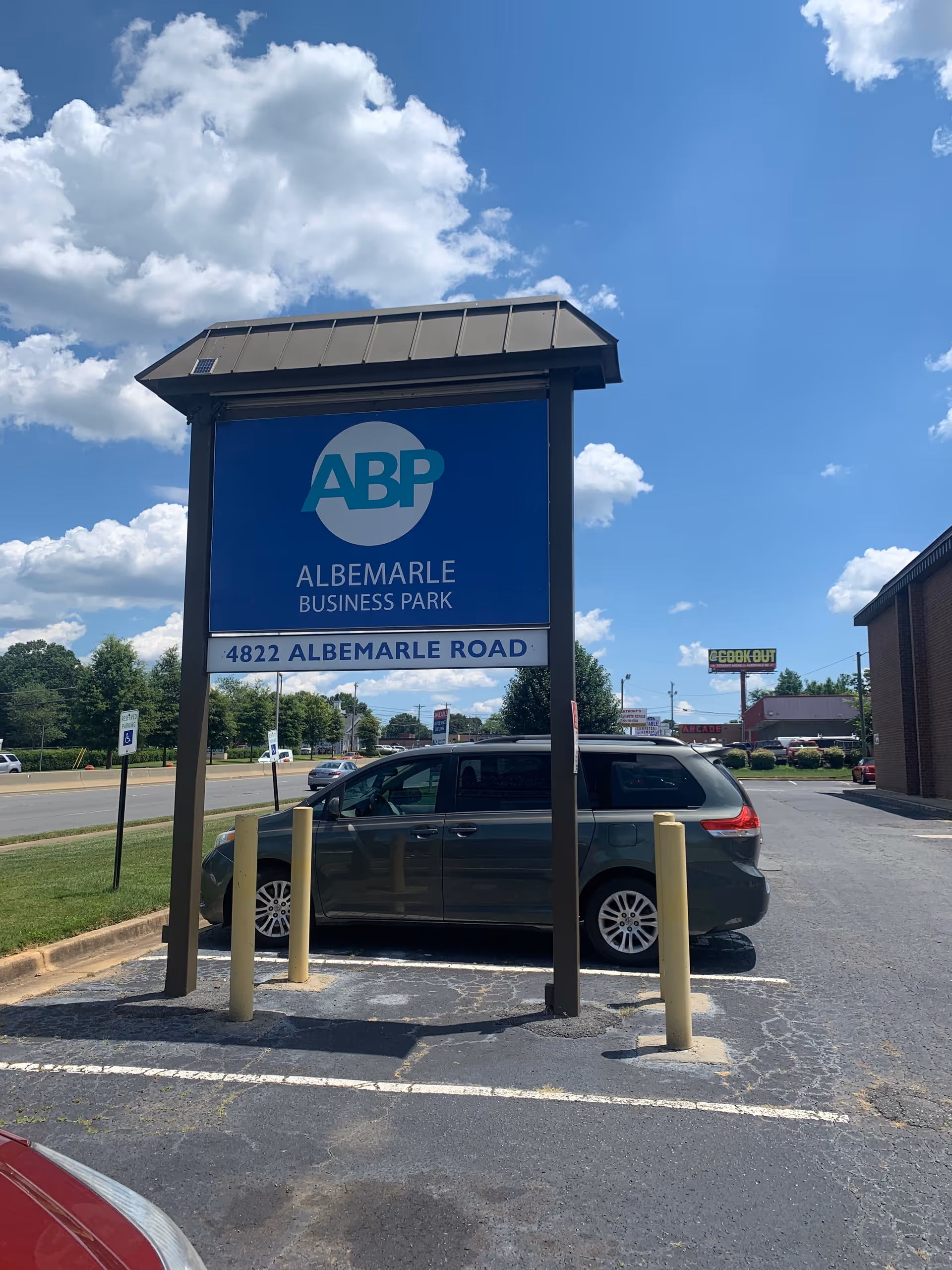 Sign for Albemarle Business Park at 4822 Albemarle Road beside a parked minivan.