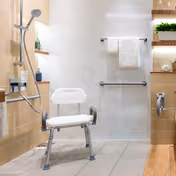 Accessible bathroom with a shower chair, grab bars, and tiled walls in a senior facility.