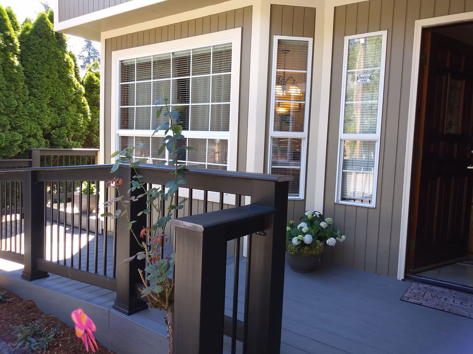 Exterior view of a senior living facility entry with a wooden deck railing and plants.