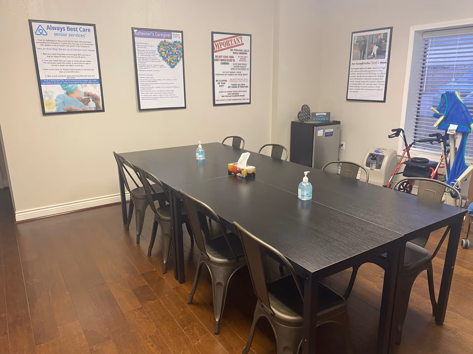 Long dark table with metal chairs in a room with posters on the wall.