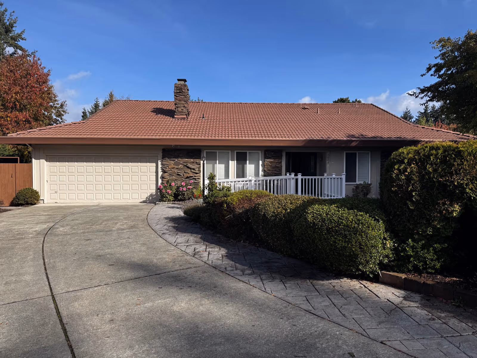Single-story senior living facility with red tile roof, driveway, and white-railed front porch.