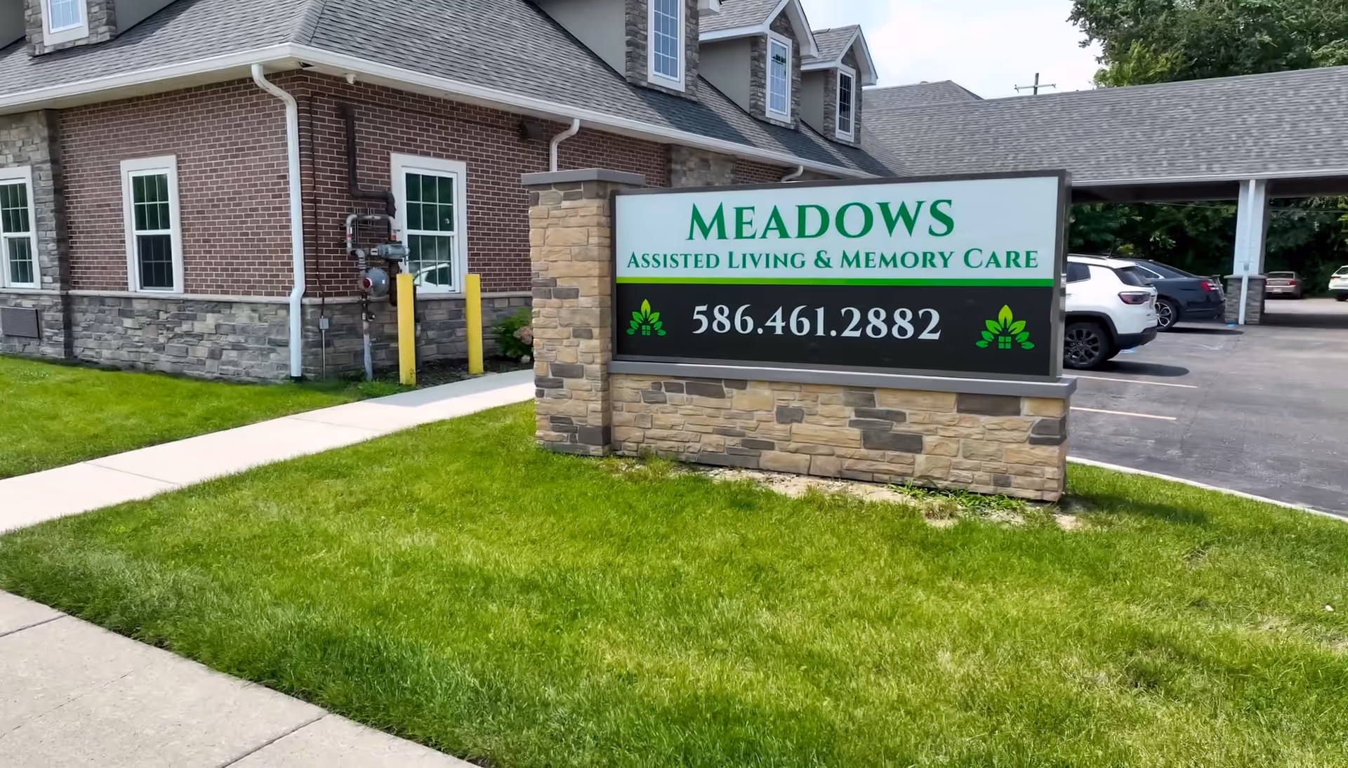 Exterior view of Meadows Assisted Living sign with brick building and parking lot.