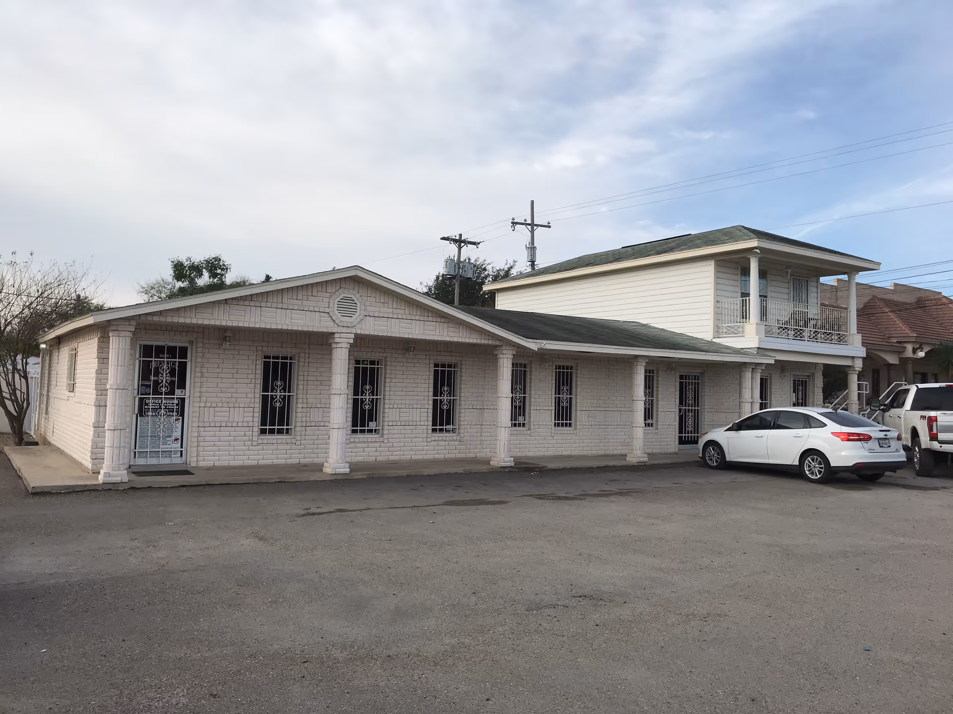 Prestige Home Care Services building: a single-story white brick facility with columns and parked cars.