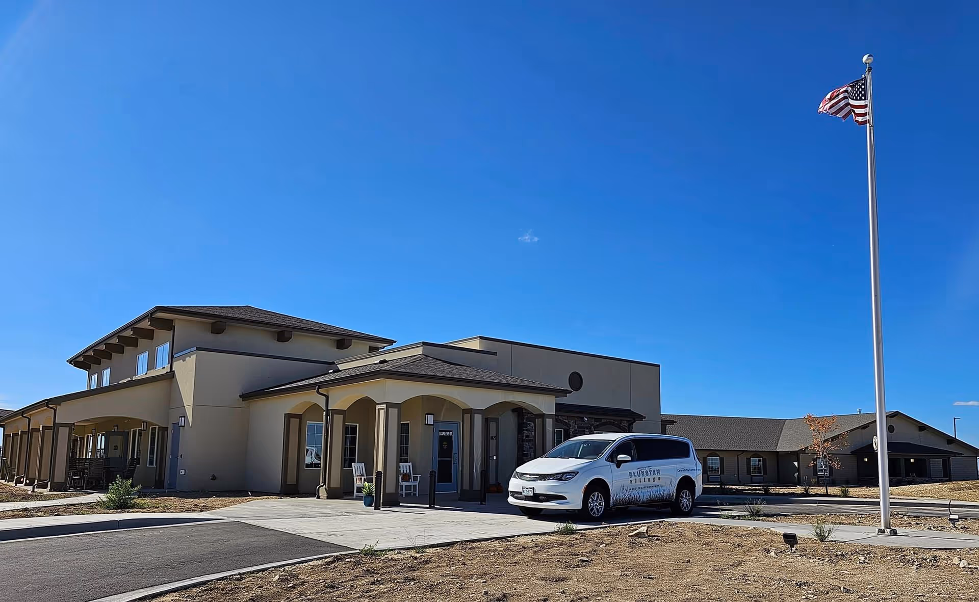 Exterior view of Bluestem Village building with a white service van and flagpole.