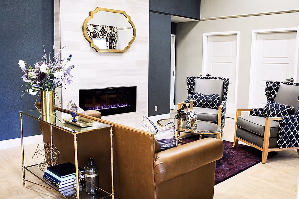 Modern lounge area with fireplace, patterned chairs, sofa, coffee table, and decor.