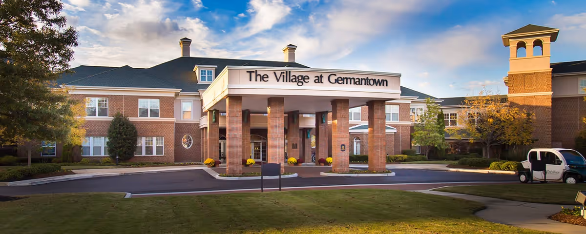 Exterior view of The Village at Germantown entrance with brick columns and signage.