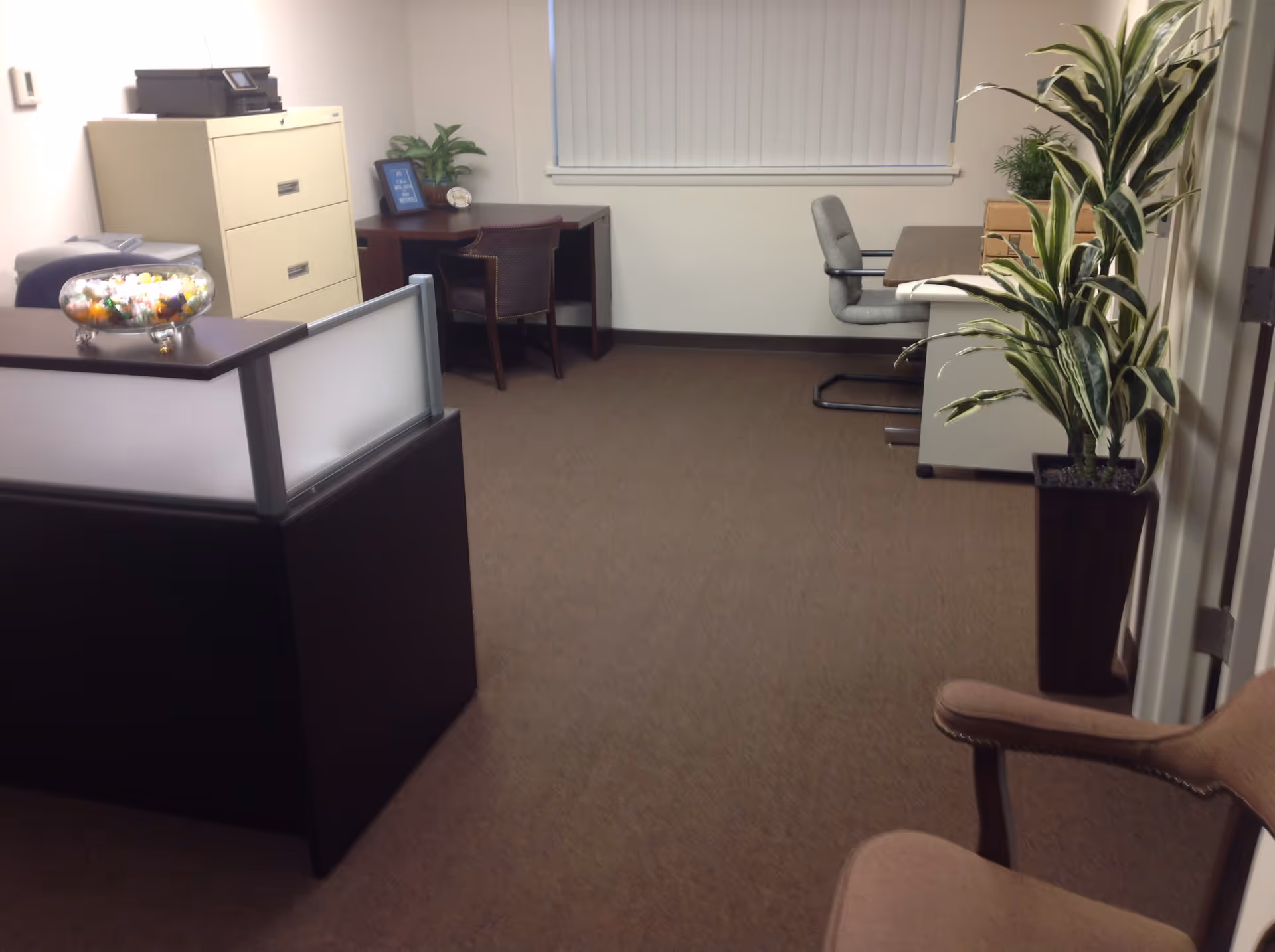 A small office area in a senior care facility with desks, cabinets, and plants.
