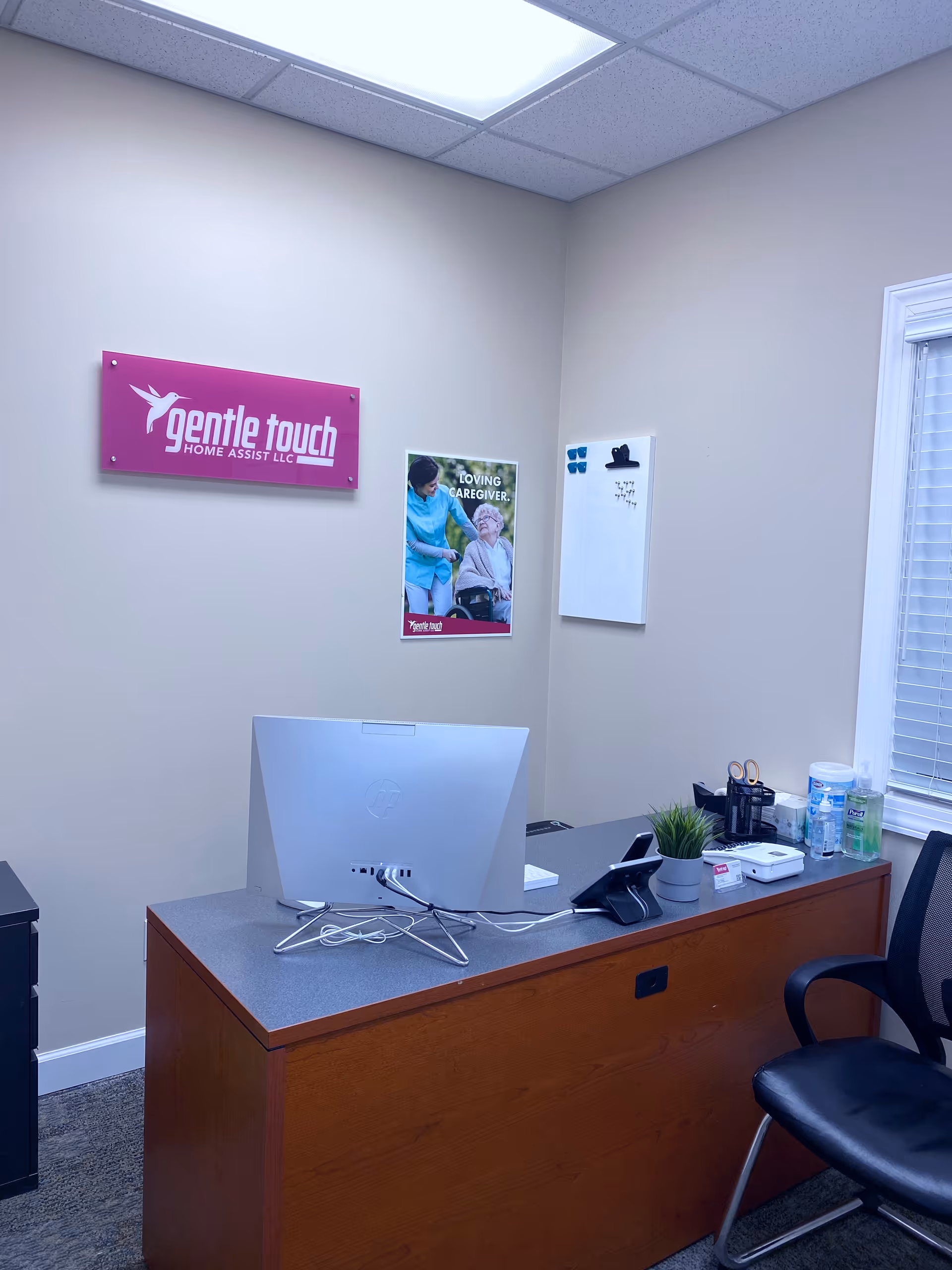 Interior office desk area featuring computer, signage for Gentle Touch Home Assist LLC.