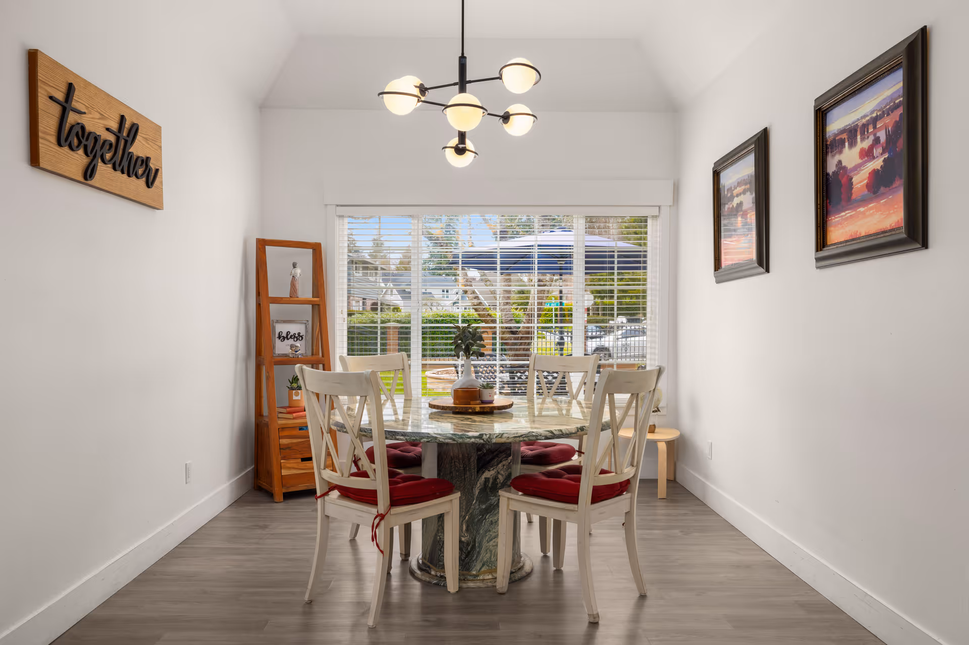 Bright dining area with a round glass table, white chairs, and large window.